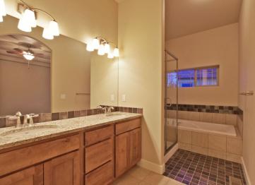 A five piece bathroom includes dual vanities, a tub, a separate standing shower and toilet.